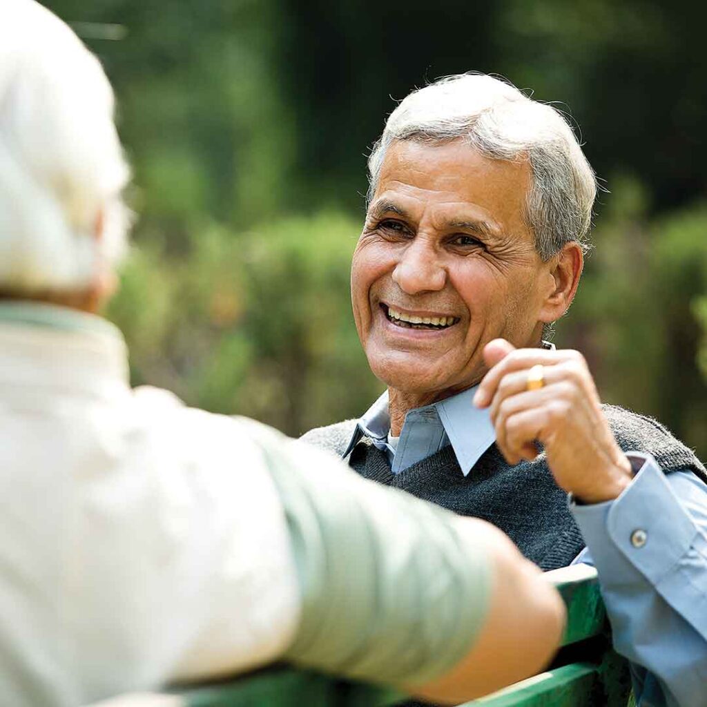 Senior man sits and talks with friend on a park bench