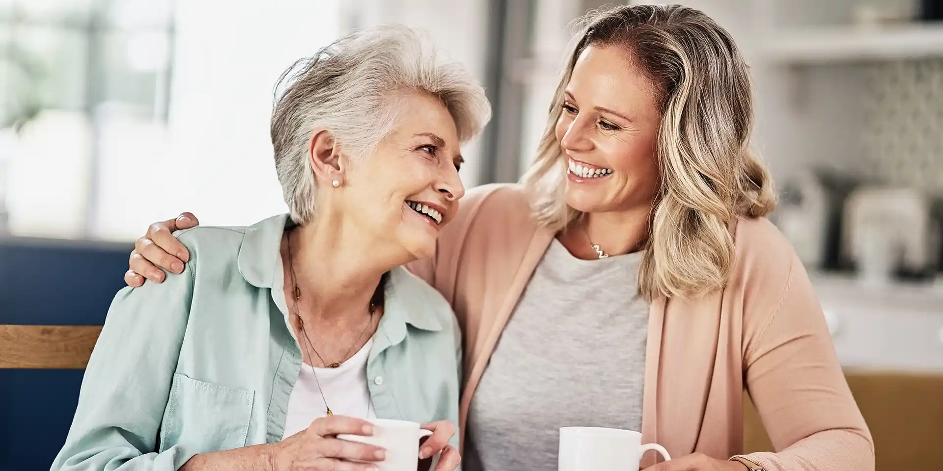 Retired mother and adult daughter enjoying a cup of coffee